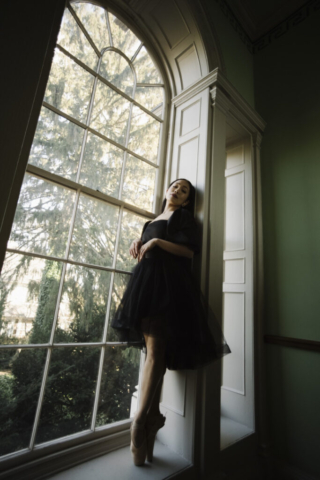 a woman wearing ballerina slippers standing in the frame of a window