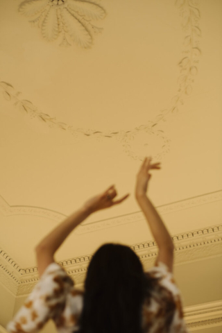 a woman with her arms up looking at the ceiling plasterwork