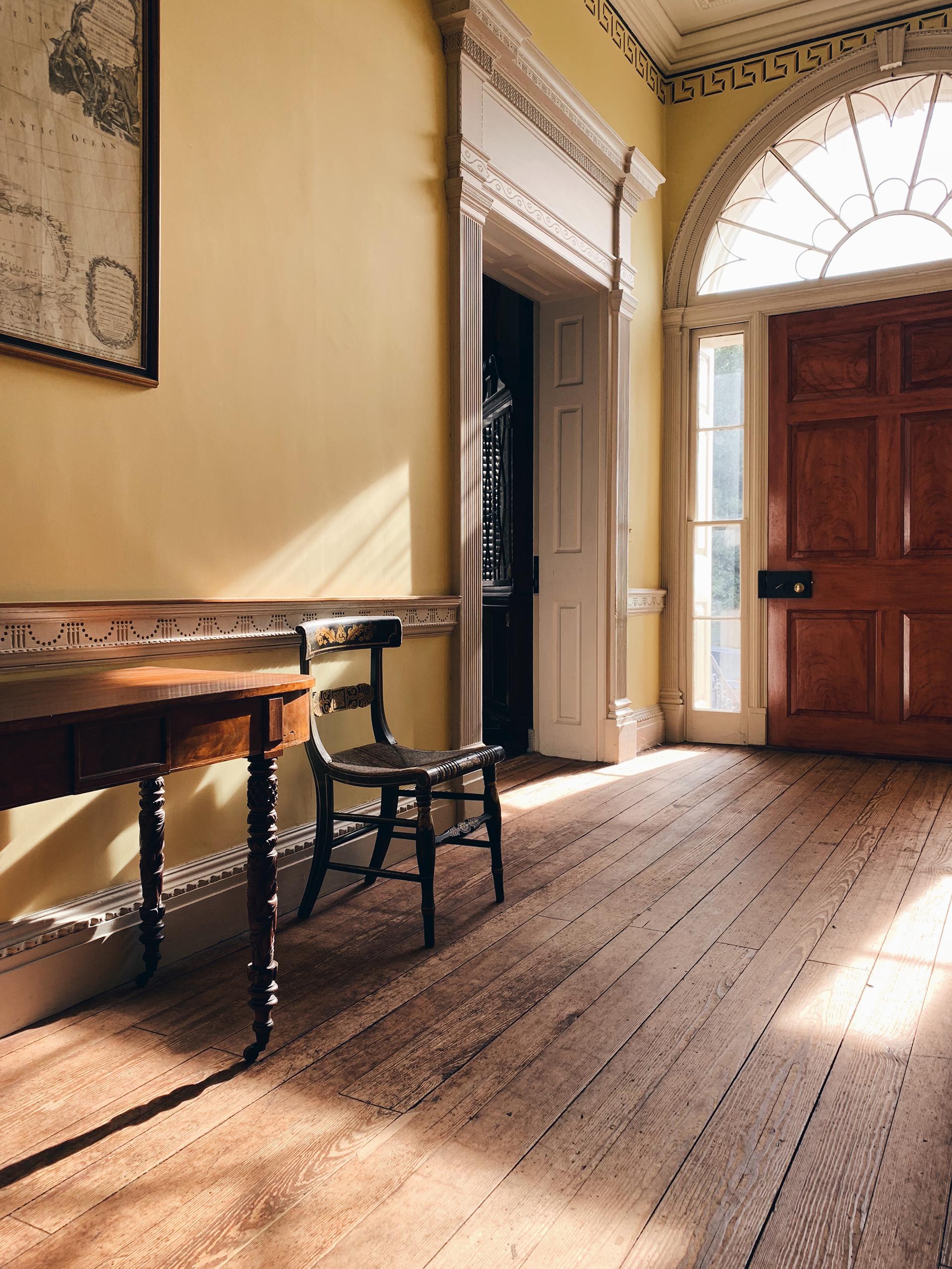 front hall interior facing the front door and a doorway to another room, with a chair and side table along the wal