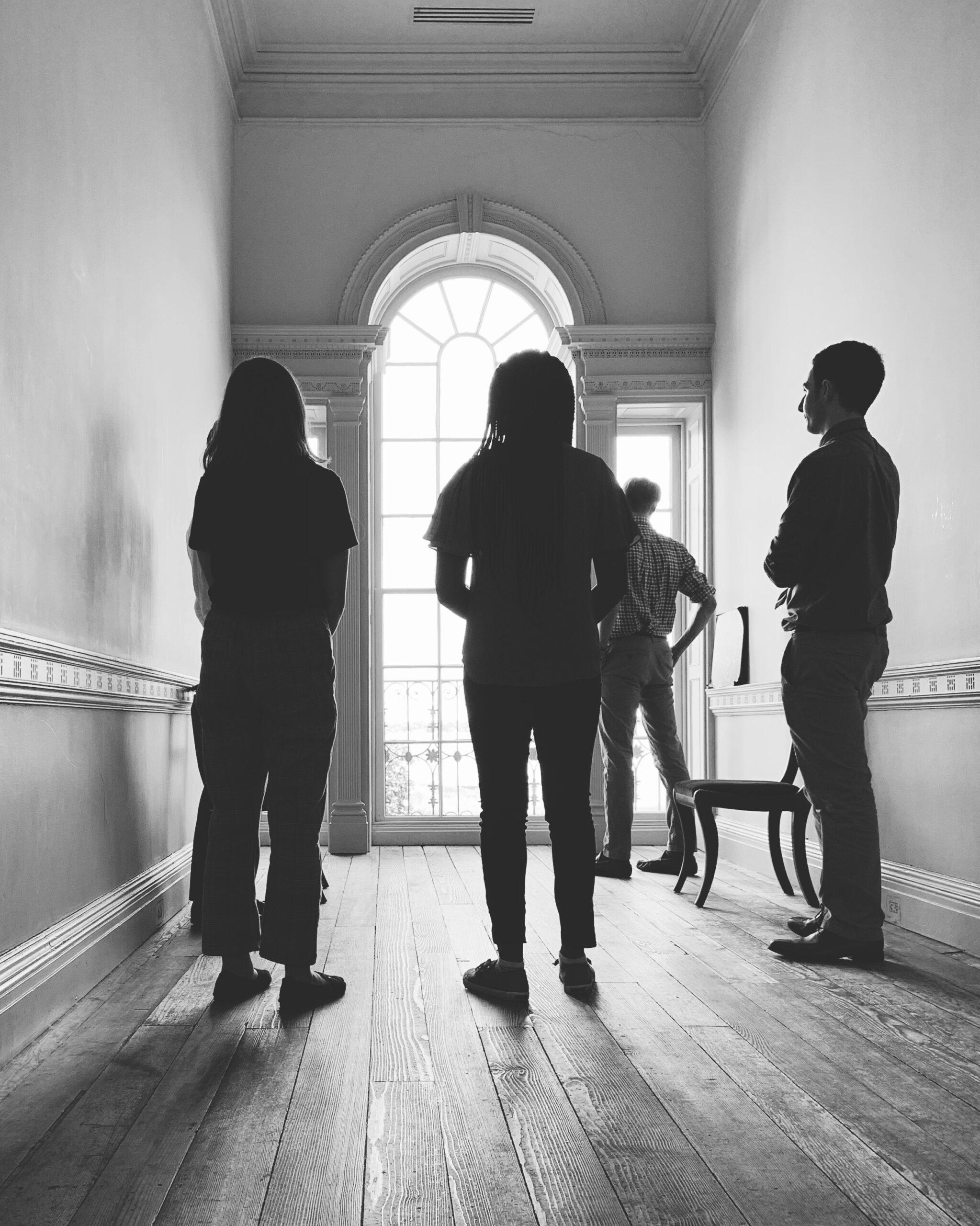 black-and-white photo of a group of people facing a window